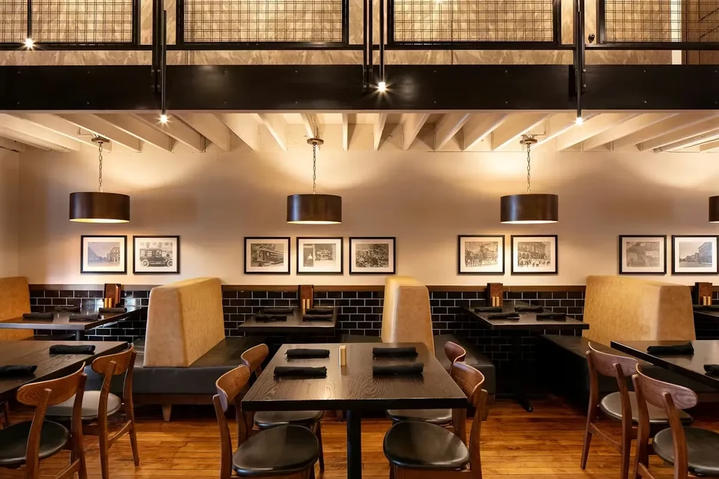 Modern empty restaurant with dark tables, tan booths, and a mezzanine.