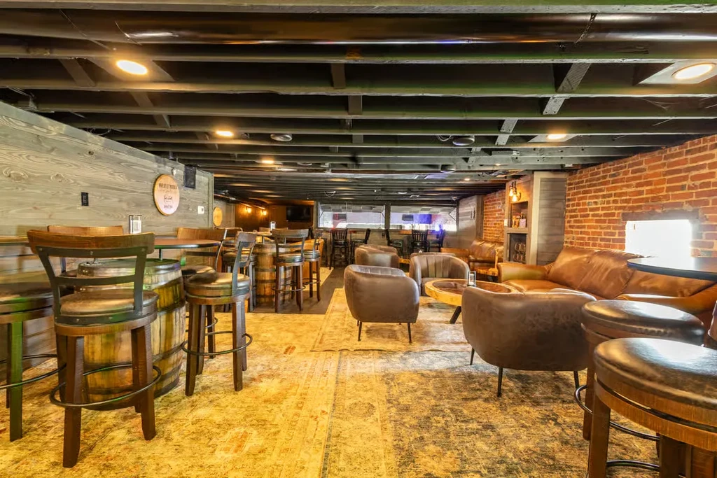 Sophisticated rustic bar interior with barrel tables and exposed brick.