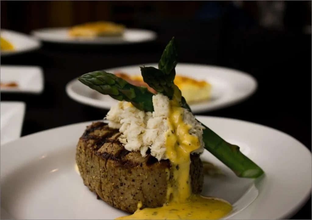 Close-up of grilled steak, crab, asparagus, and creamy sauce.