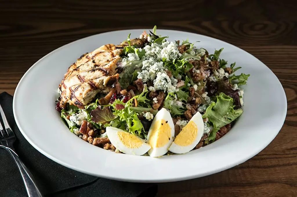 Grilled chicken salad with blue cheese, nuts, cranberries, and eggs.