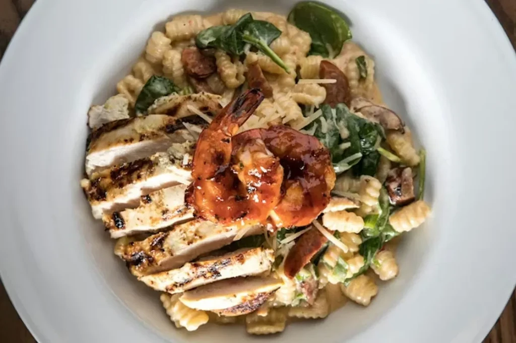Pasta dish with grilled chicken, shrimp, spinach, and creamy sauce.