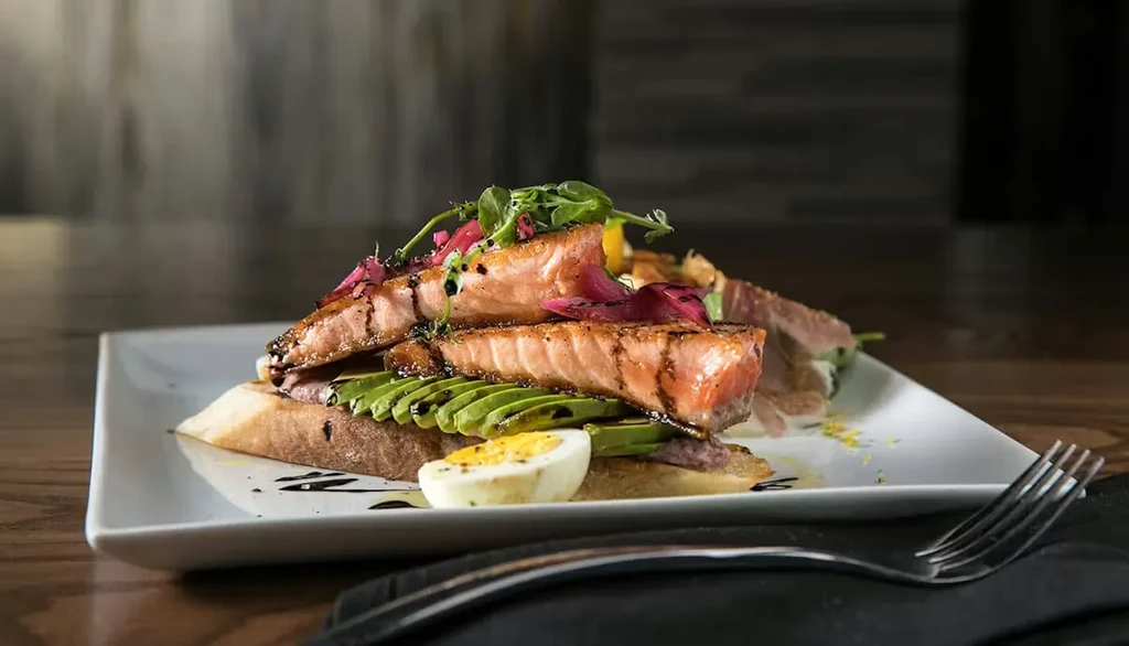 Grilled salmon toast with avocado, egg, microgreens, pickled onions, balsamic.