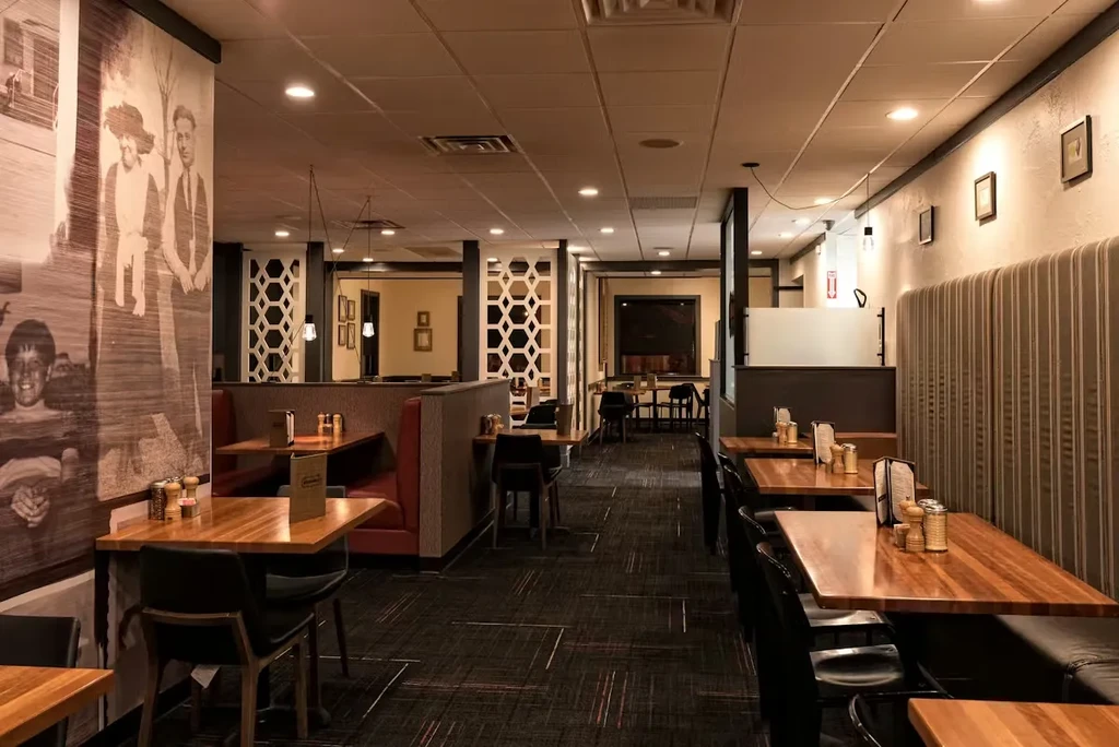 Modern restaurant with red and black booths, wooden tables, and a mural.
