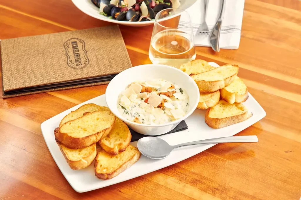 Overhead of creamy dip, baguette, wine, and Michaelangelo's menu.
