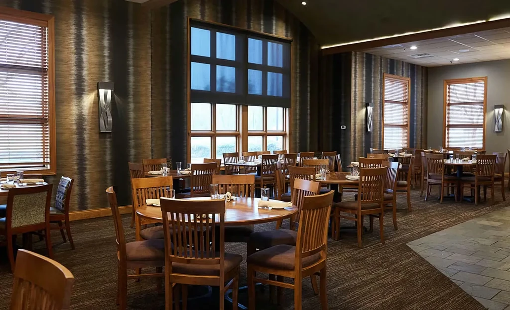 Spacious, empty restaurant dining area with set wooden tables and chairs.
