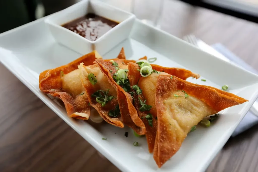 Crispy golden-brown fried wontons with green onions and dipping sauce.