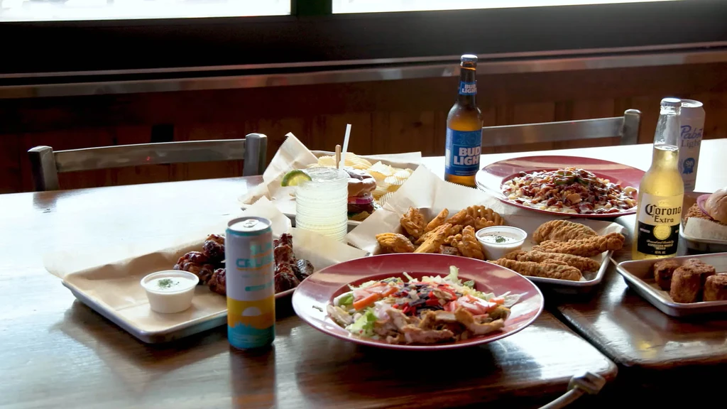 Wooden table laden with nachos, chicken, salad, and various drinks.
