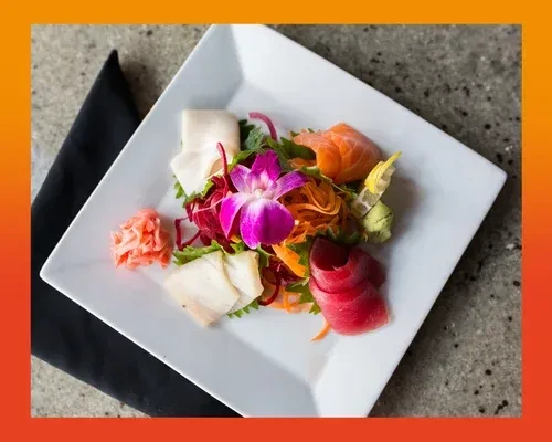 Assorted sashimi plate with salmon, tuna, ginger, wasabi, and orchid.