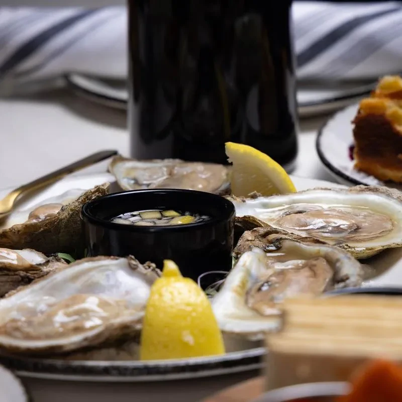 Plate of fresh oysters on the half shell with lemon and sauce.