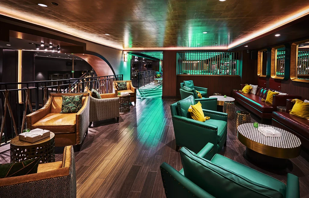 Luxurious restaurant lounge with emerald green seating, gold ceiling, green glow.