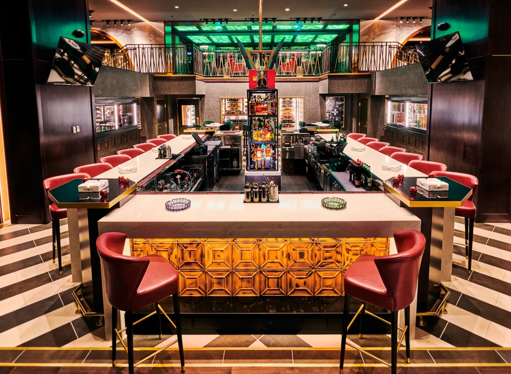 Luxurious modern bar with illuminated U-shaped counter, striped floor, green lighting.