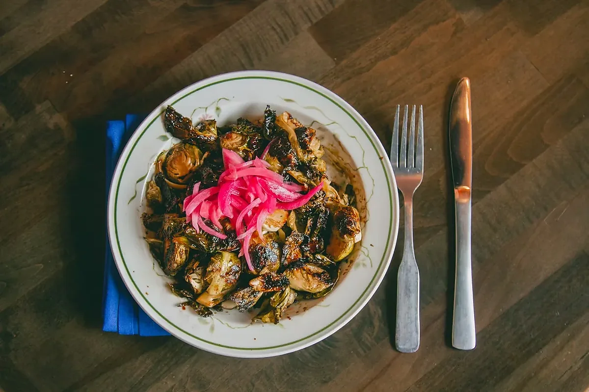 Roasted brussels sprouts with pickled red onion on rimmed plate