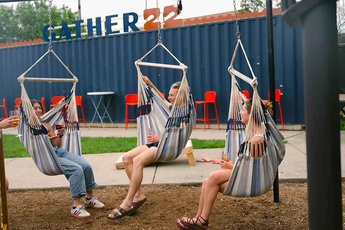 People with drinks in hanging hammock swings on outdoor patio