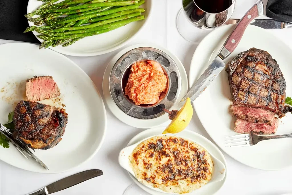 Overhead: upscale table with steaks, asparagus, seafood, and gratin.