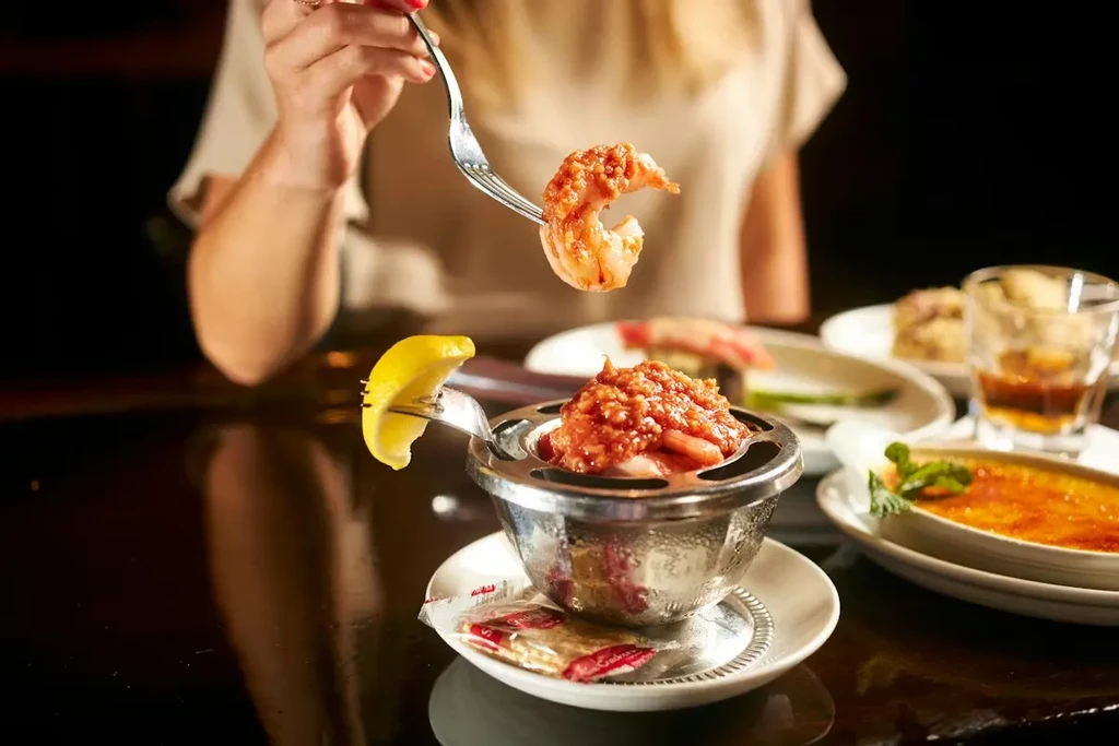 Close-up of hand lifting shrimp from a cocktail dish.