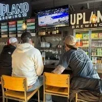 Three patrons watch basketball on TV at Upland Brewing.