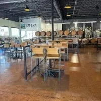 Upland Brewing Co. industrial interior with barrels and seating.