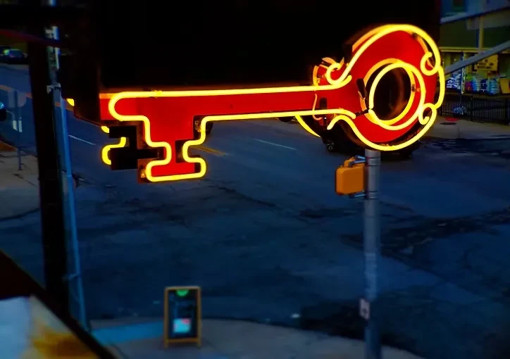 Large neon antique key sign glows red and yellow at night.