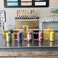 Various beers and ciders displayed on a bar counter with taps.