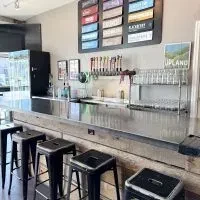 Upland brewpub bar counter with beer taps, stools, and a menu board.