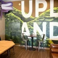 Casual restaurant interior: UPLAND mural, small table, bar stools, booth.