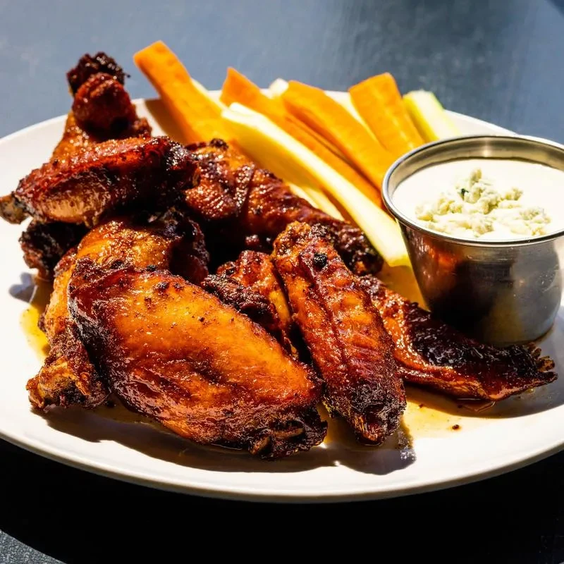 Plate of crispy chicken wings with blue cheese dip, carrots, and celery.