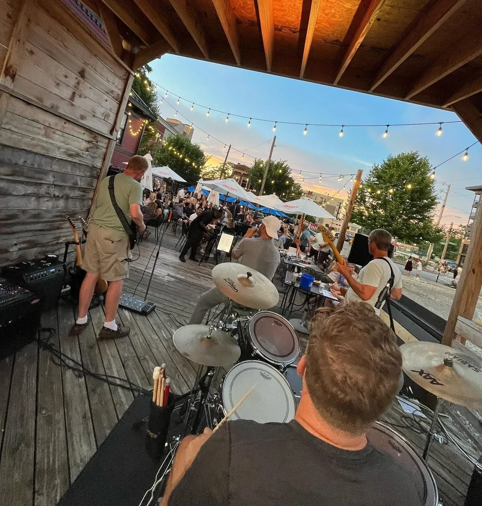 Band plays on an outdoor patio with diners under string lights.