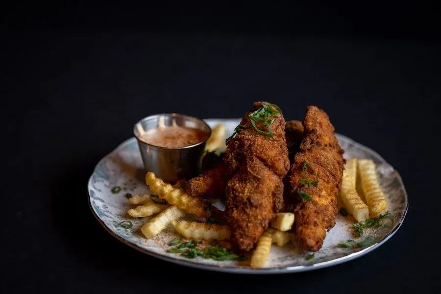 Golden fried chicken tenders, crinkle fries, and pink dipping sauce.