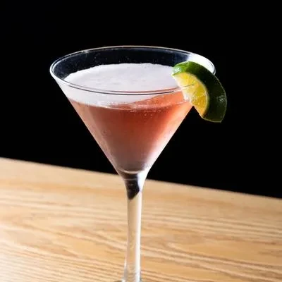 Frothy, two-toned cocktail in martini glass garnished with a lime.
