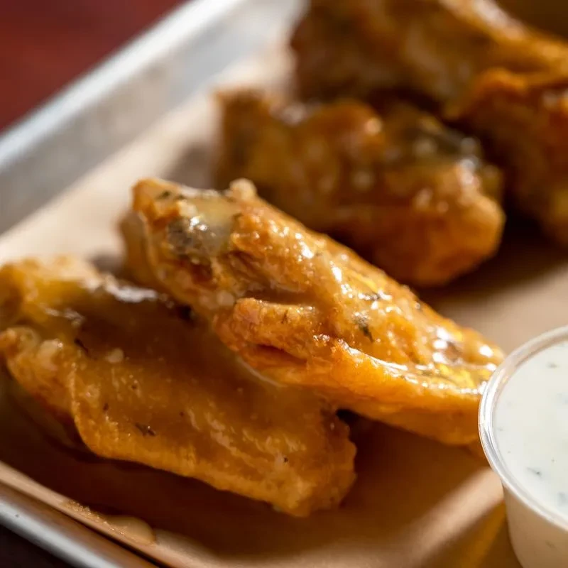 Golden-brown glazed chicken wings with a creamy dipping sauce.