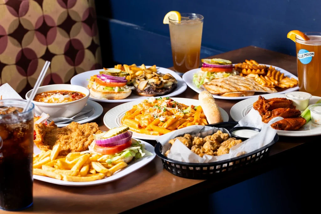 Restaurant table filled with diverse American dishes, drinks, no people visible.