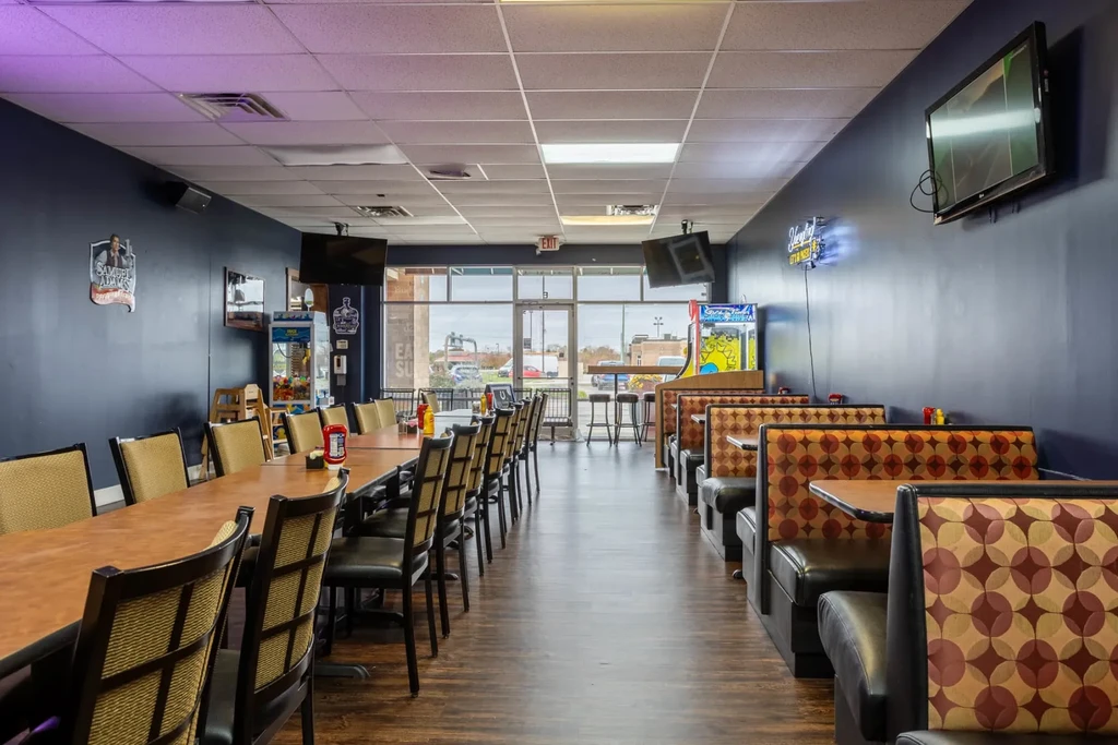 Empty casual restaurant interior with patterned booths, tables, and blue walls.