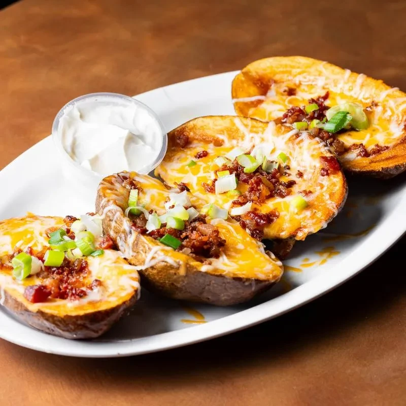Plate of four loaded potato skins with sour cream.