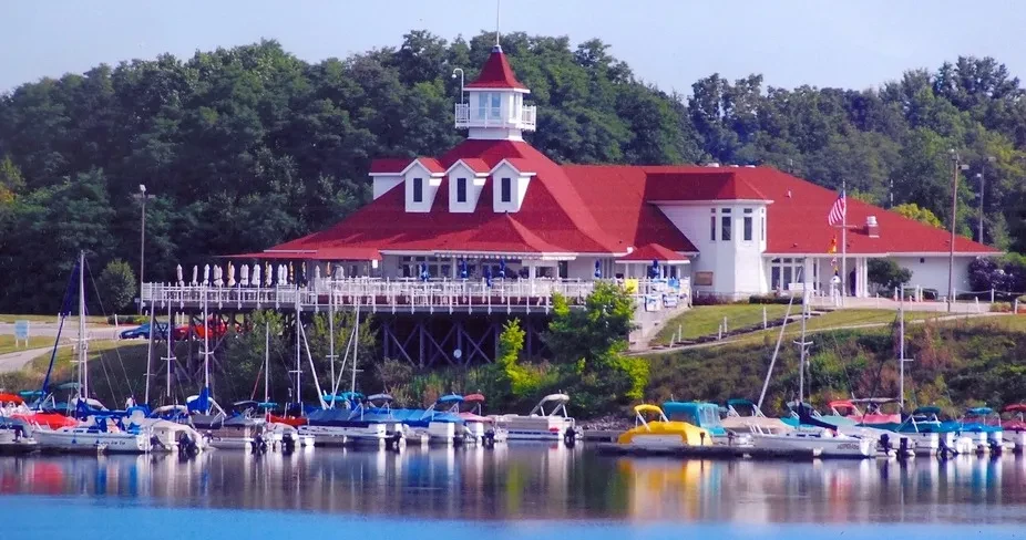 Red-roofed waterfront building with patio and numerous docked boats.