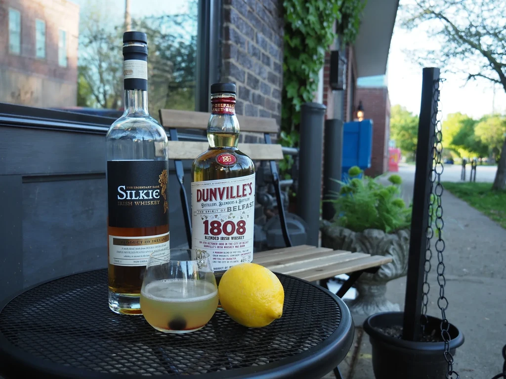 Silkie and Dunville's Irish whiskey, cocktail, and lemon on an outdoor table.