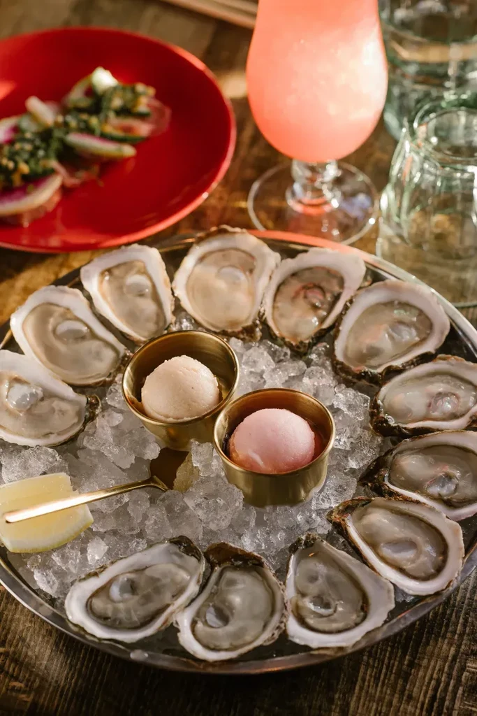 Close-up of fresh oysters on ice tray with sorbet and lemon.