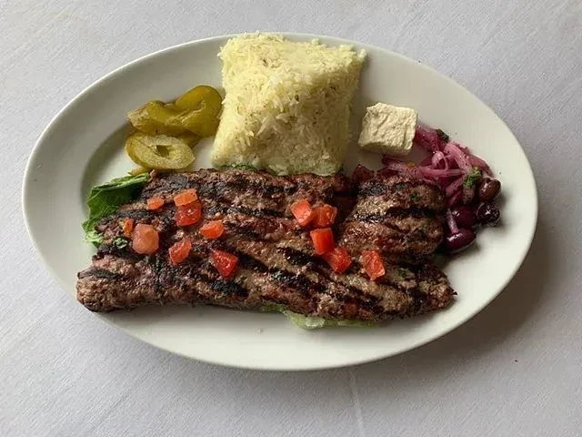 Grilled meat with rice, lettuce, pickled peppers, feta, and onion relish.