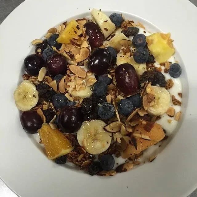Overhead view of a colorful yogurt parfait with fruit, nuts, and granola.