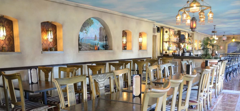 Elaborate Middle Eastern restaurant interior with ornate decor, tables, and bar.