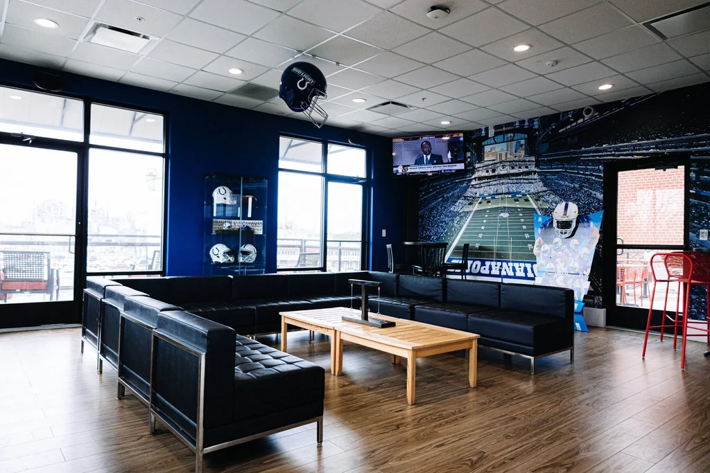 Modern Indianapolis Colts-themed sports lounge with helmets, mural, and TV.