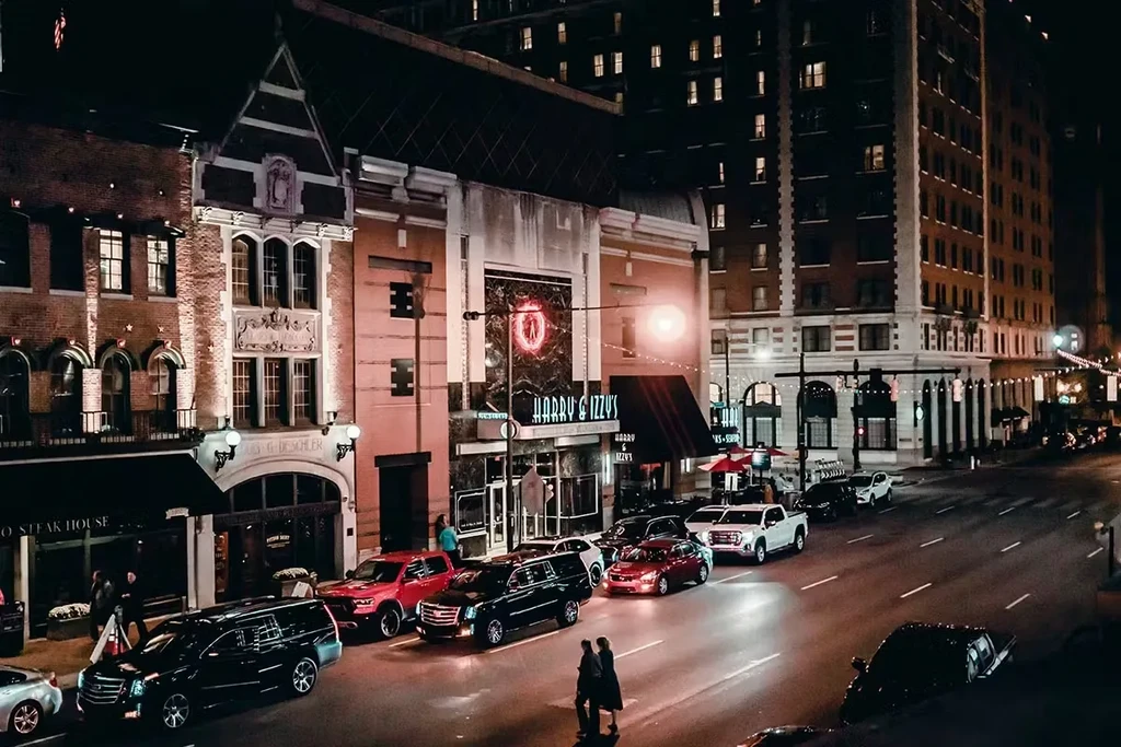 Nighttime urban street scene with Harry & Izzy's and other restaurants.