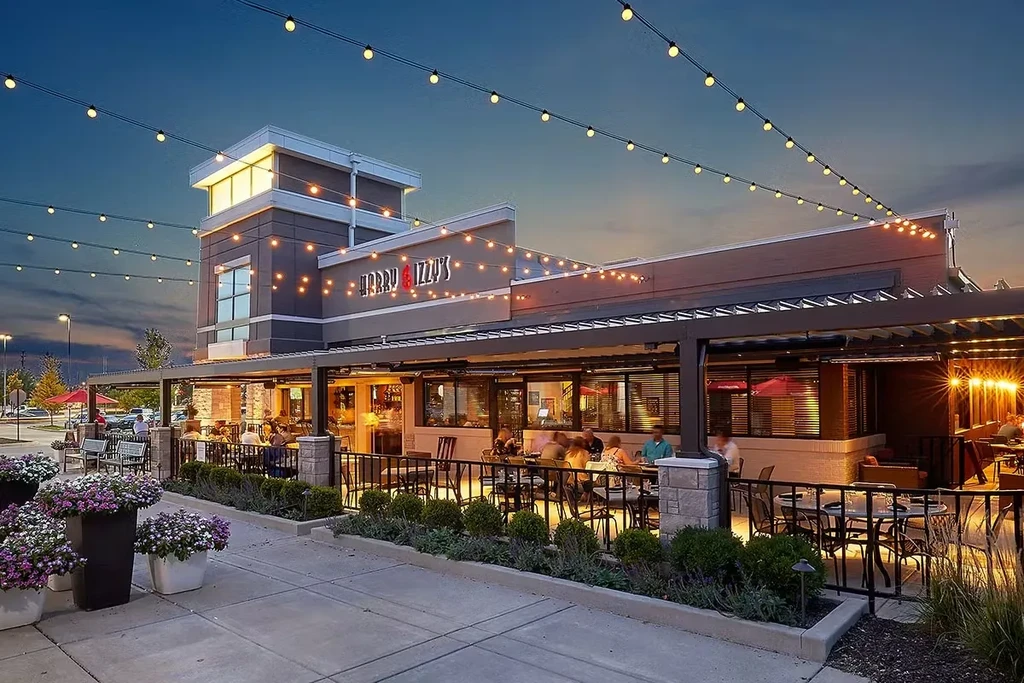 Exterior of Harry & Izzy's restaurant at dusk with a busy, lit patio.