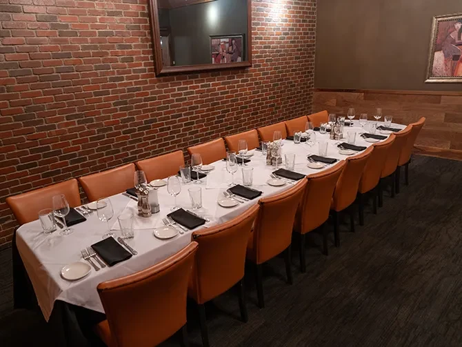 Long dining table set for a group with white plates, leather chairs.