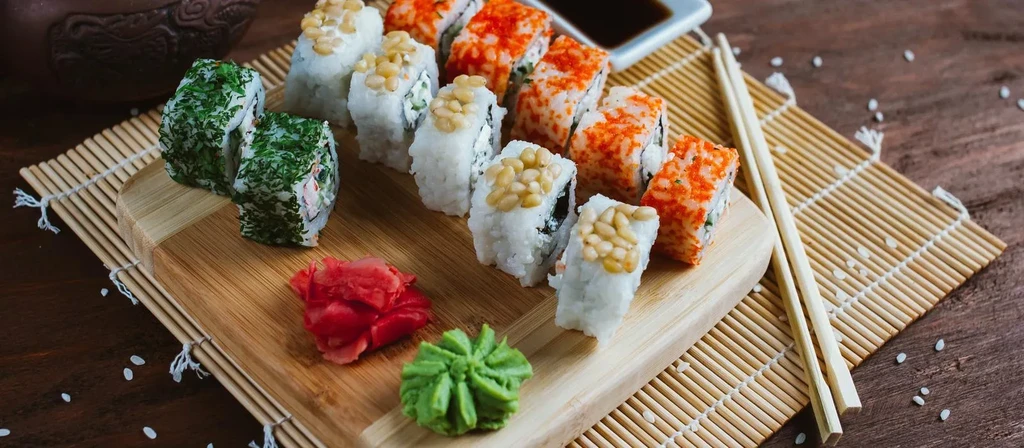 Sushi rolls with green herbs, pine nuts, tobiko, ginger, wasabi, soy sauce.