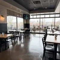 Empty modern industrial restaurant dining area with large windows.