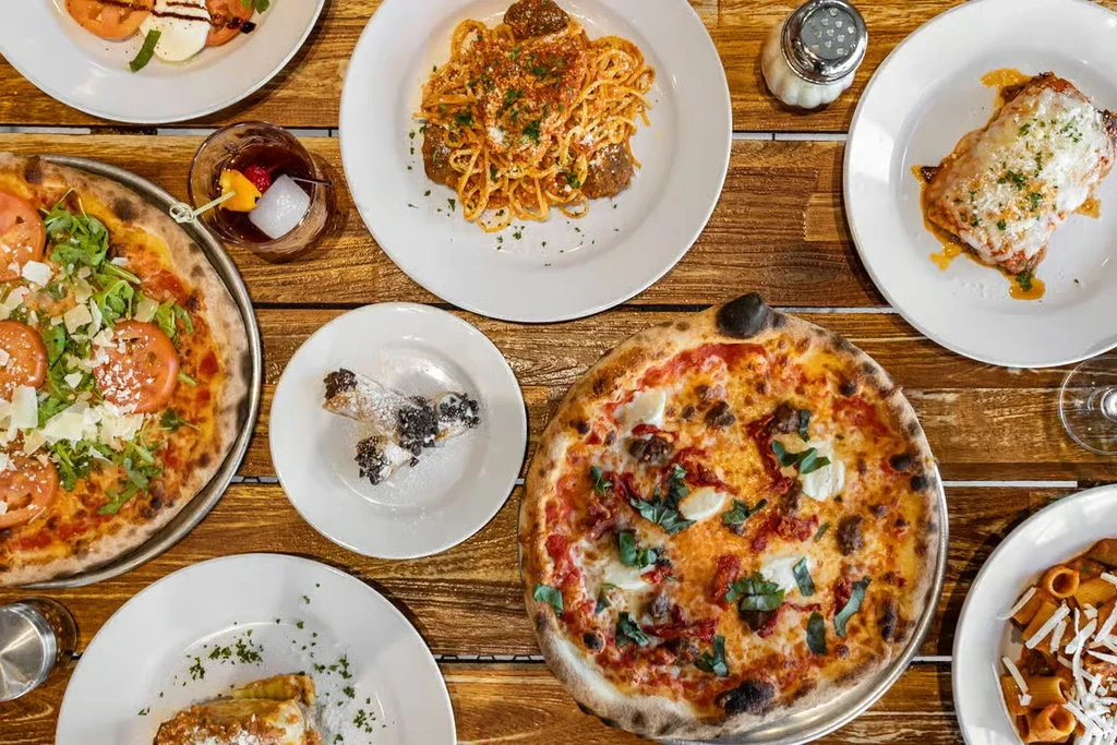 Top-down view of a wooden table laden with Italian food and drinks.