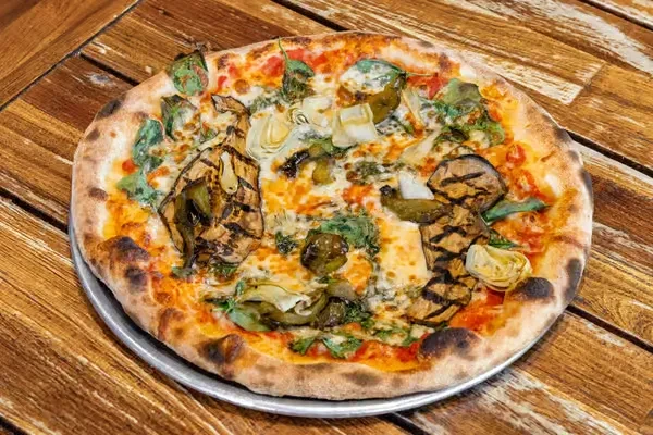 Charred Neapolitan pizza with eggplant, artichoke, and greens on wood.