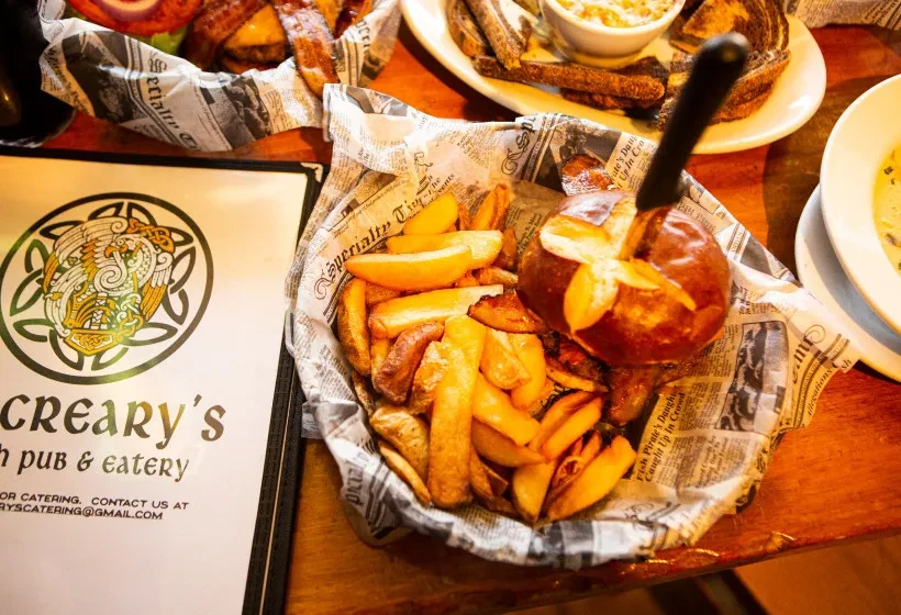 Fries, pretzel bun, and Creary's Irish Pub menu on a wooden table.