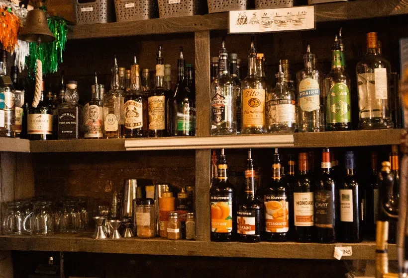 Wooden bar shelves brimming with diverse liquor bottles, wine, and barware.