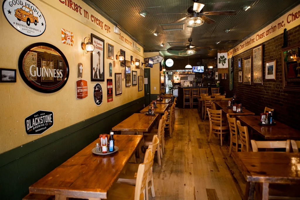 Empty, rustic pub dining area with brewery signs and bar.